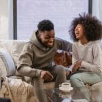 Śmiejąca się para na kanapie w salonie podczas rozmowy