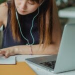 Studentka notuje przy laptopie podczas nauki pisania rozprawki