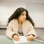 Studentka pisząca test w sali, odwraca wzrok od kartki