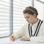 Uczeń piszący wypracowanie na egzaminie w jasnej sali szkolnej