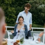 Uśmiechnięta para rozmawia przy kolacji na świeżym powietrzu z przyjaciółmi