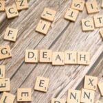 Drewniane płytki Scrabble układające się w słowo death na starej desce