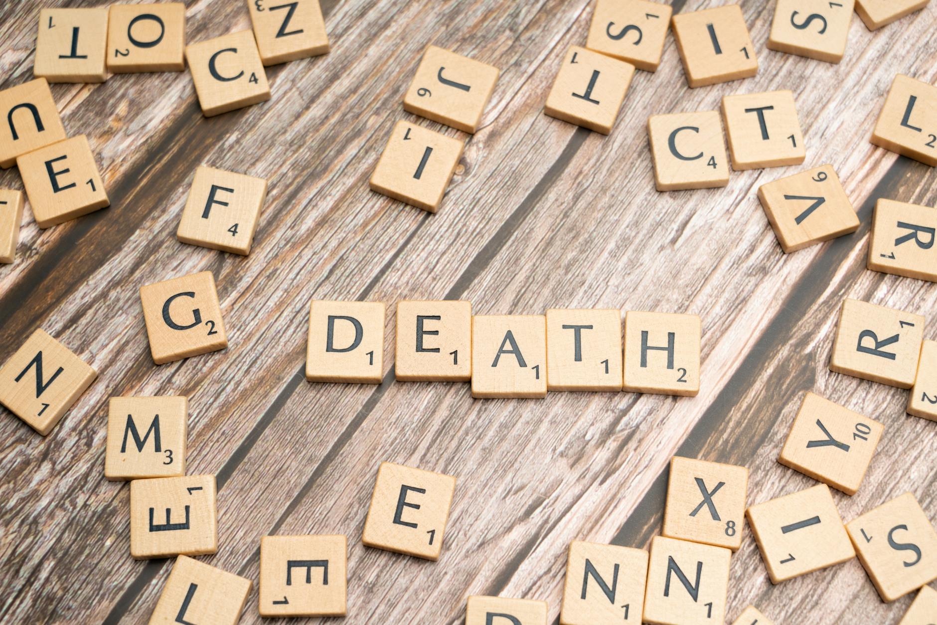 Drewniane płytki Scrabble układające się w słowo death na starej desce