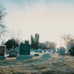 Osoba zamyślona przy nagrobku na cmentarzu o wschodzie słońca