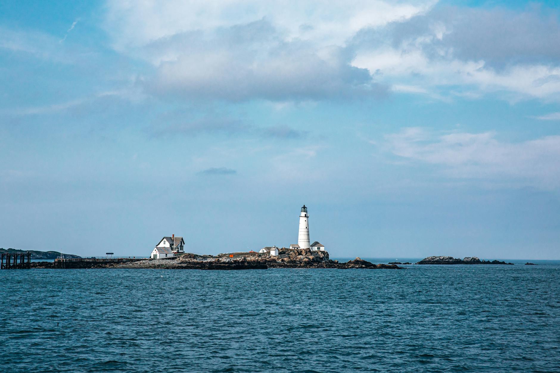 Latarnia morska Boston Lighthouse na tle spokojnego morza i błękitnego nieba