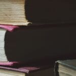Stos starych książek w twardych oprawach związanych z literaturą